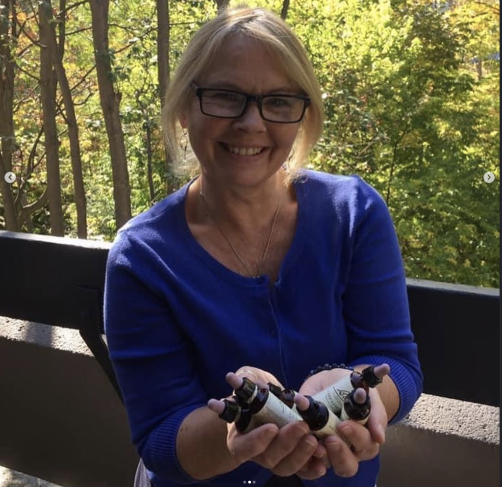 Meet Linsey Denham: Helping Women Find Their Way Back to Themselves 1 Linsey Denham, Emotional Support Specialist, smiles outdoors while holding several Bach Flower Remedy bottles. Surrounded by trees, the image reflects Linsey’s holistic approach to helping others find greater emotional balance, peace and wellbeing.